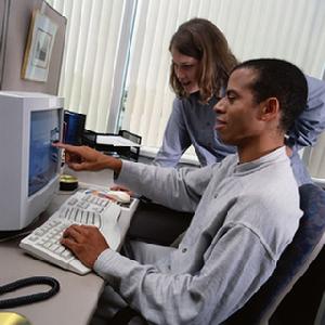 Man pointing at a monitor with a female coworker by his side